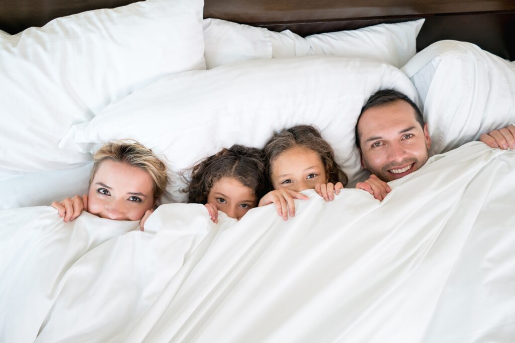 Happy family in bed under the covers looking playful - lifestyle concepts